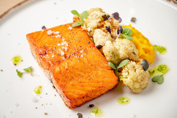 A beautifully plated dish featuring grilled salmon, complemented by cauliflower and smooth mash