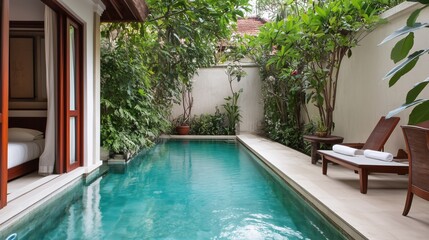 A pool with a wooden deck and a patio area with a bench and a chair. The pool is surrounded by trees and plants, creating a serene and relaxing atmosphere