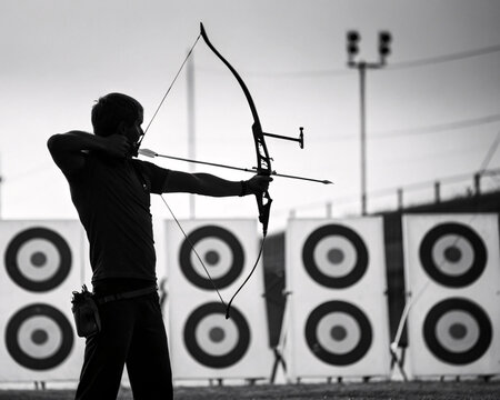 Silhouette of an Archer Drawing a Bow and Arrow in Black and White