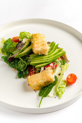 A vibrant winter salad features crispy tofu atop fresh greens and cherry tomatoes, plated elegantly