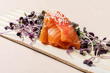 A beautifully arranged salmon fillet is topped with tiny pearls, resting on a bed of microgreens