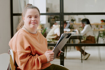 Medium close up portrait of Caucasian woman with down syndrome holding clipboard with documents © AnnaStills