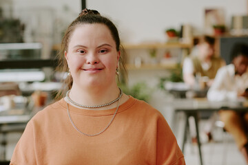 Medium close up portrait of happy female office worker with down syndrome posing for photo in modern office © AnnaStills