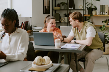 Obraz premium Wide shot of Caucasian colleagues sitting together and having friendly conversation while on lunch break in office