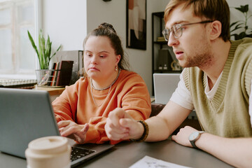 Medium close up of two Caucasian colleagues focused on developing new app for computers while working in office