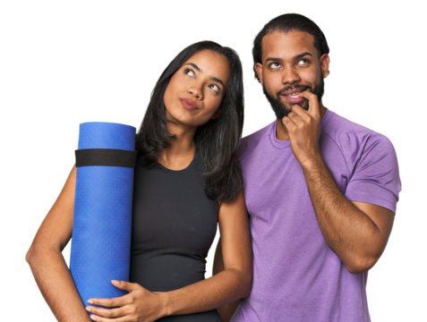 Athletic Latino couple with yoga mat relaxed thinking about something looking at a copy space.