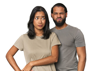 Fototapeta premium Young Latino couple in studio confused, feels doubtful and unsure.