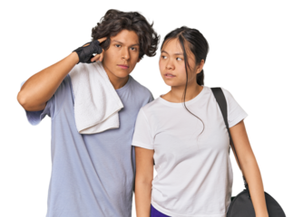 Young interracial athletic couple in studio pointing temple with finger, thinking, focused on a task.