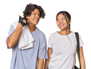 Young interracial athletic couple in studio showing a mobile phone call gesture with fingers.