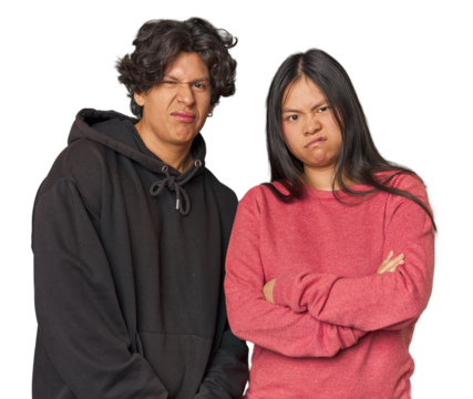 Young interracial couple in studio frowning face in displeasure, keeps arms folded.