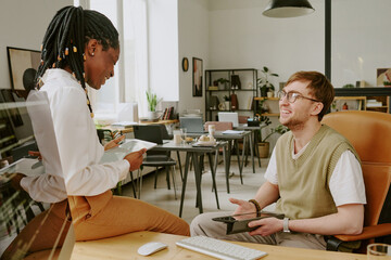 Medium close up of young biracial friends resting after shift in office, joking and enjoying...
