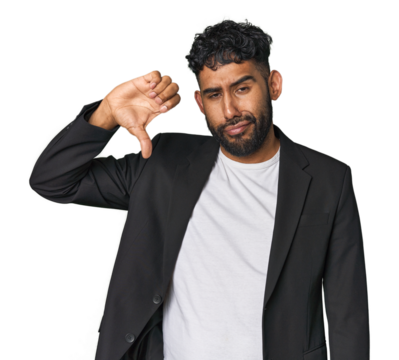 Hispanic businessman in suit in studio showing thumb down, disappointment concept.