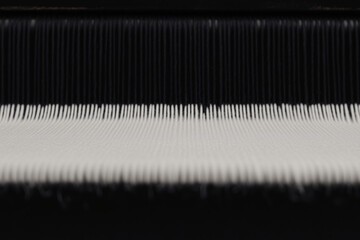 Industrial Fabric Creation: Close-up of a weaving machine in operation, creating rows of woven fabric, capturing the detail of the threads and machinery.