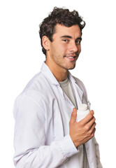 Young Hispanic pharmacist with pills looks aside smiling, cheerful and pleasant.
