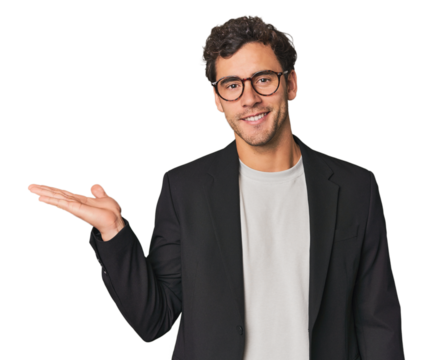 Young Hispanic businessman showing a copy space on a palm and holding another hand on waist. - Powered by Adobe