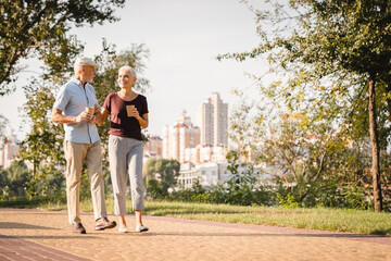 Happy senior couple family walking in summer city park enjoying retirement and spending time...