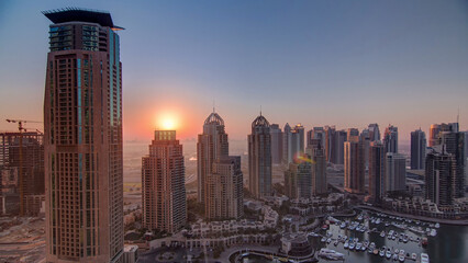 Fototapeta premium Sunrise in Dubai Marina with towers and harbor with yacht from skyscrappers rooftop, Dubai, UAE timelapse