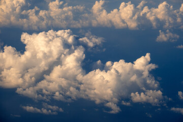 Aerial view from airplane window at high altitude of dense puffy cumulus clouds flying