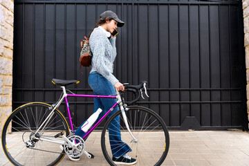 Young woman walking with her bicycle and talking on the phone