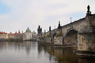 Charles bridge crossing vltava river in Prague with cloudy sky