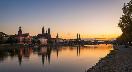 Fototapeta premium Riverfront Serenity: Mainz Skyline at Sunset - Golden Reflections on the Rhine
