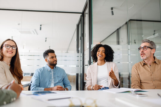 Diverse professionals engaged in a dynamic team meeting. The group discusses ideas and strategies in a bright and modern office, fostering collaboration and innovation.