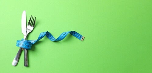 Red tape measure with cutlery on color background, top view. The concept of losing weight