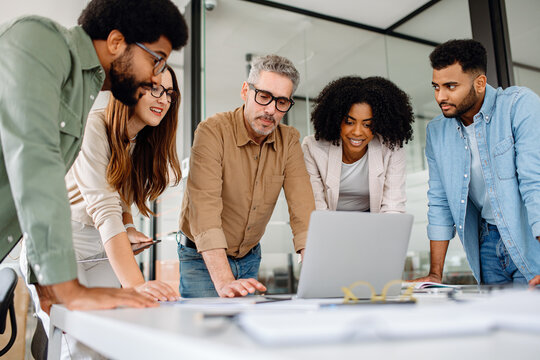 Business professionals reviewing performance charts and analyzing company growth in office environment. Multicultural team working together, discussing financial data and planning business strategies