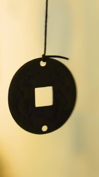  A Chinese lucky coin A Chinese lucky coin with a hole inside spins around its axis. The coin is on strings. The money amulet brings wealth in Asian countries. 