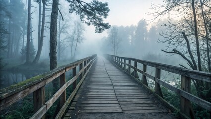 Fototapeta premium Wooden bridge disappearing into misty forest in early morning