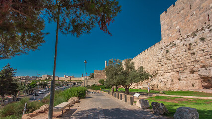 Fototapeta premium Defensive wall of the ancient holy Jerusalem timelapse hyperlapse, lit by the bright sun. Wonderful green lawn