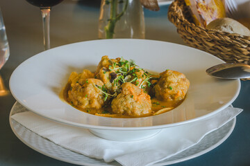 A bowl of food with meatballs and vegetables