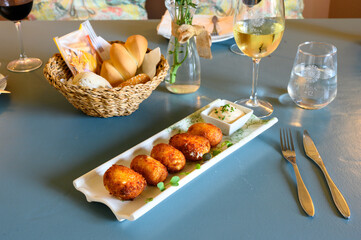 A plate of food with a basket of bread and a glass of water
