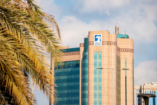 19 January 2025, Abu Dhabi, UAE: Adnoc headquarters rising majestically behind a palm tree, showcasing the modern architecture