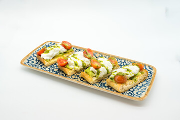 A plate of four small breads with cheese and tomato sauce