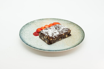 A chocolate dessert with nuts and strawberries on a plate