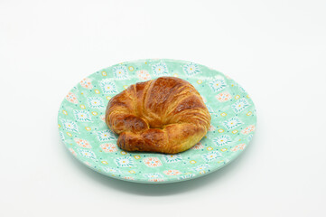 A croissant is on a plate with a floral pattern