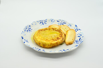 A plate of food with a yellow pancake and a piece of bread