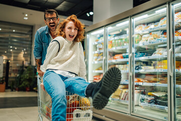Couple having fun riding shopping cart in supermarket