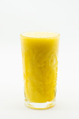 A glass of yellow liquid is sitting on a white background