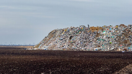 Obraz premium Landfill site with piled waste under cloudy sky, environmental pollution, waste management, recycling awareness concept