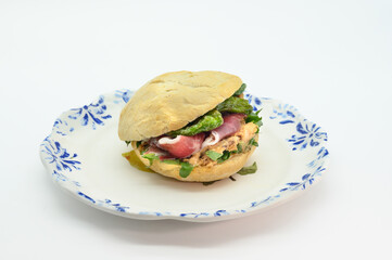 A sandwich is on a white plate with a blue border