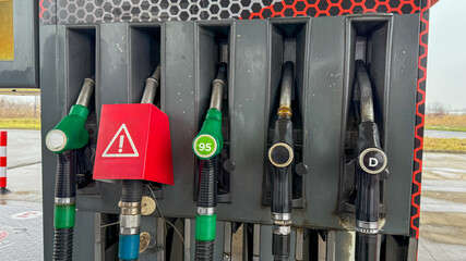 Fuel pump station nozzles with warning sign, energy concept, automotive travel, transportation infrastructure, gasoline options