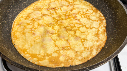 Golden pancake cooking in a skillet, perfect for breakfast or Shrove Tuesday celebrations, food concept