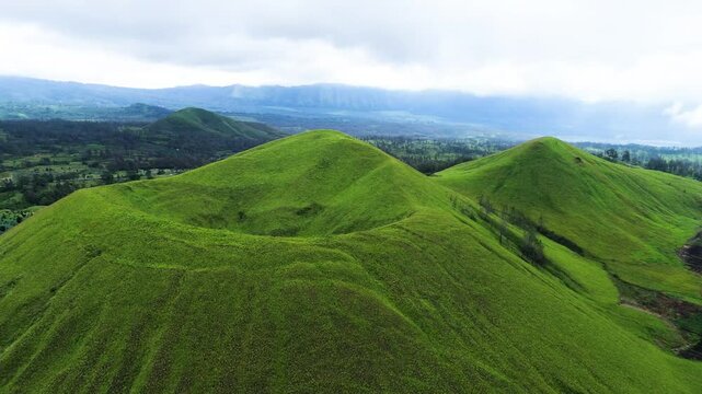 aerial view of green hills peak with grassland and mountain views of Wurung Crater, Indonesia. Aerial shot of the green grassy peak of the mountain crater.