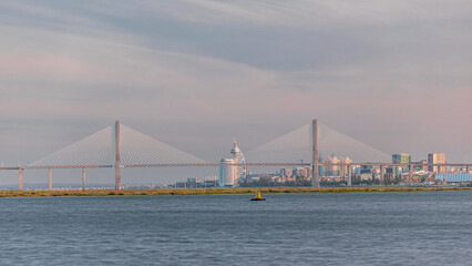Vasco da Gama Bridge over river Tagus timelapse in Lisbon with park of Nations district modern architecture, Portugal