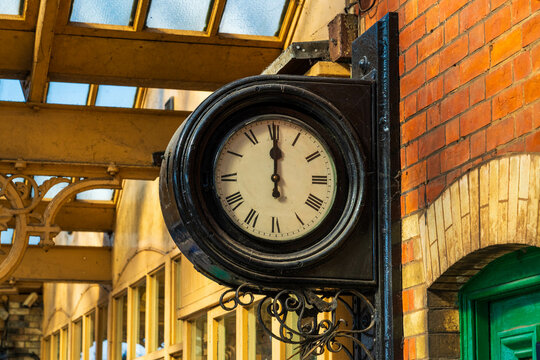 Retro antique clock at a train station, Old analog clock showing twelve o'clock
