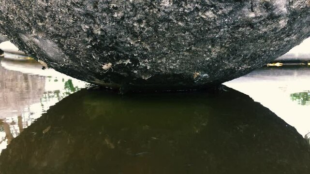 Small fish swim in the fountain under a large stone ball