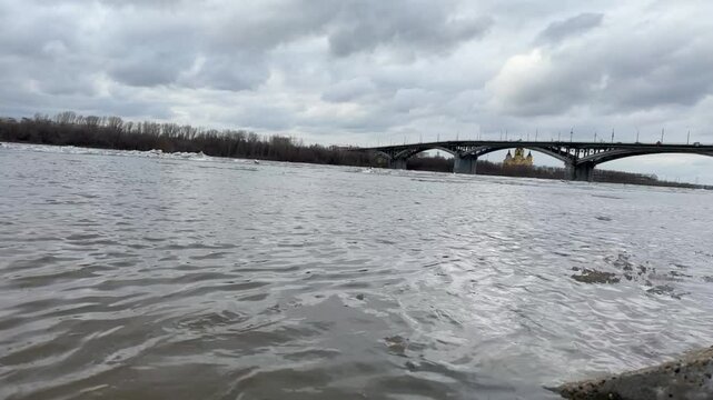 Bridge spans a river with a cloudy sky above. The water is murky and the bridge is partially submerged