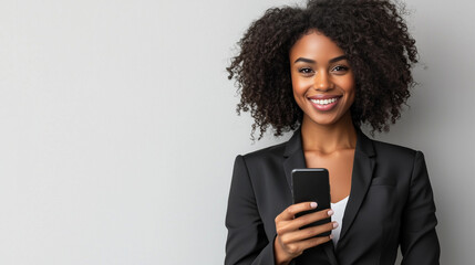 Fototapeta premium Confident young African American businesswoman with smartphone in suit